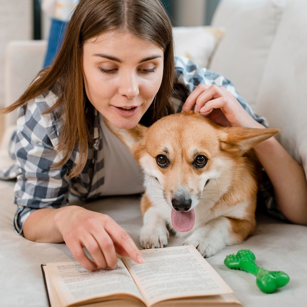 Free photo front view of woman reading book with dog on couch