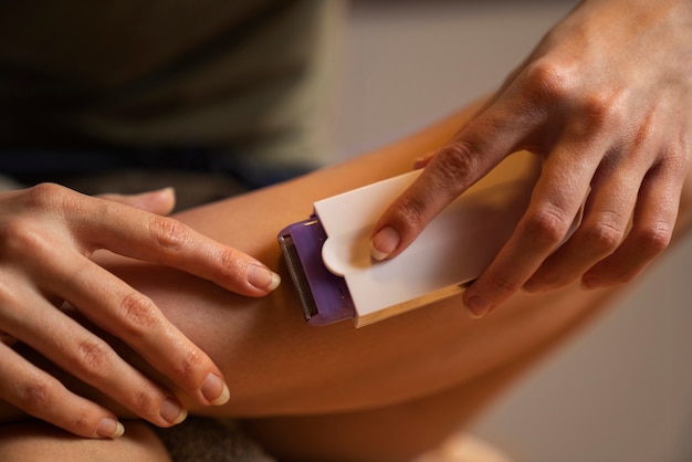 Free photo front view woman shaving leg