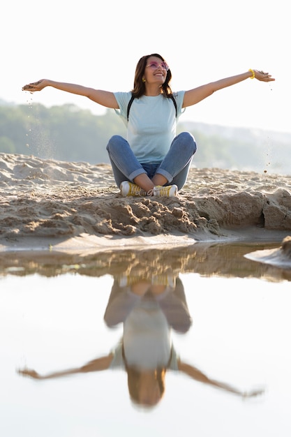 Free photo front view of woman sitting on beach sand