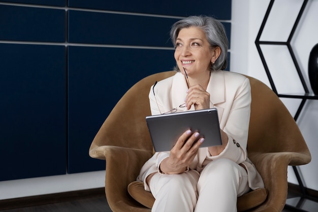 Front view woman sitting on chair with tablet