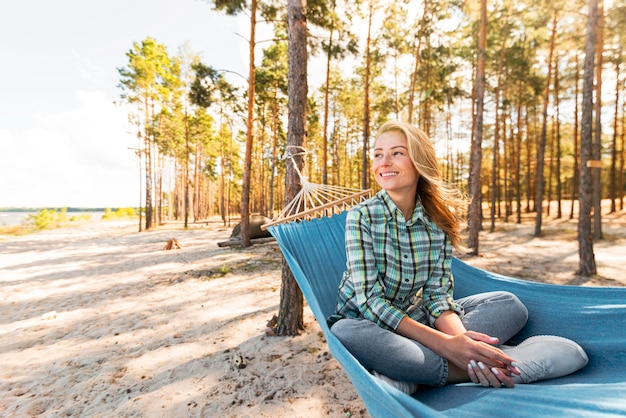 Free photo front view woman sitting in hammock and looking away