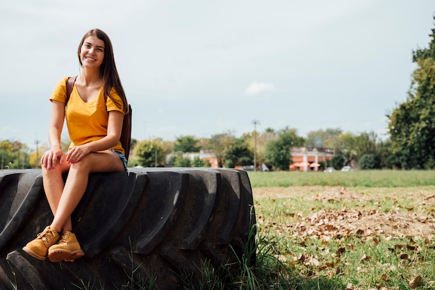 Free photo front view of woman sitting on tractor wheel