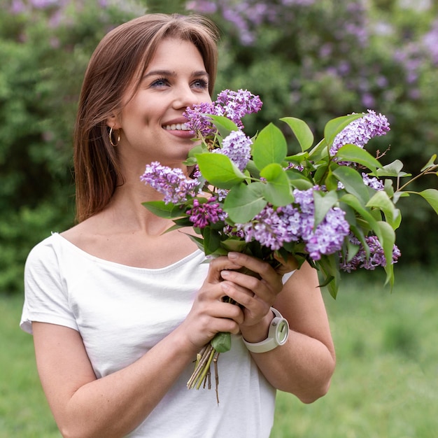 Free photo front view woman smelling lilac bouquet