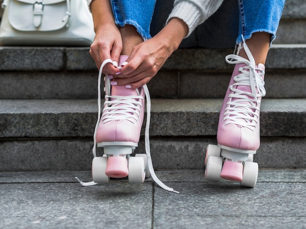 Free photo front view of woman on stairs tying shoelaces on roller skates