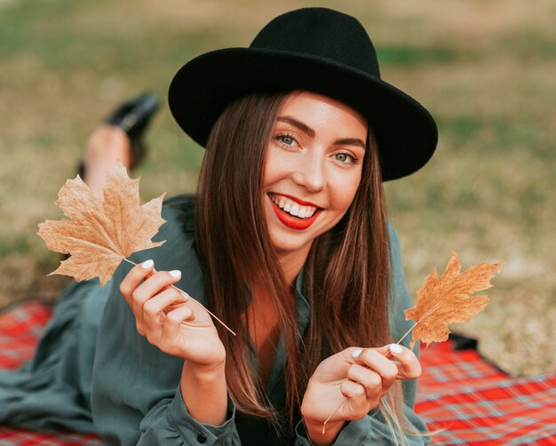 Front view woman staying on a blanket while holding some dry leaves