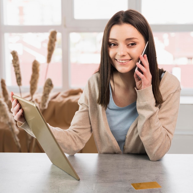 Front view of woman talking on the phone and holding tablet