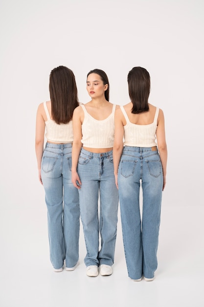 Front view of woman in tank top and jeans standing next to other women with turned backs