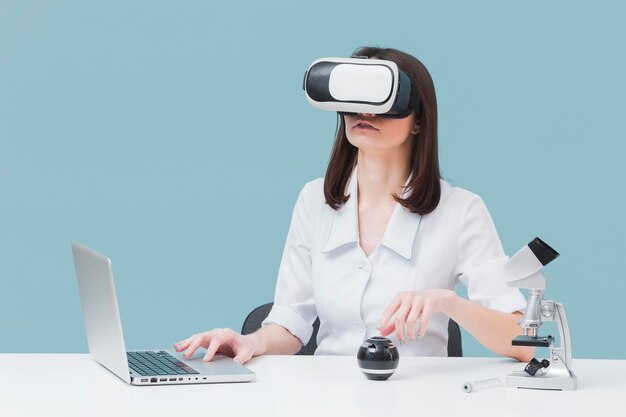 Front view of woman using laptop and virtual reality headset