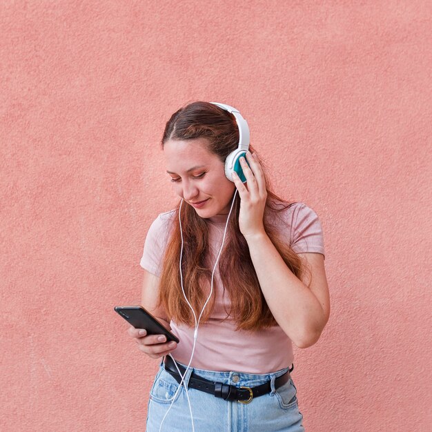 Front view of woman using smartphone and headphones to listen to music