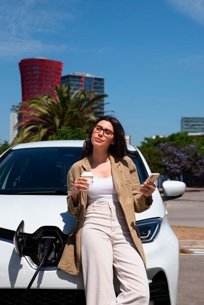 Front view woman waiting for the car to charge