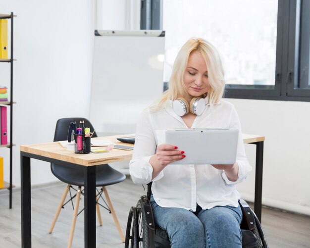 Front view of woman in wheelchair at the office holding tablet