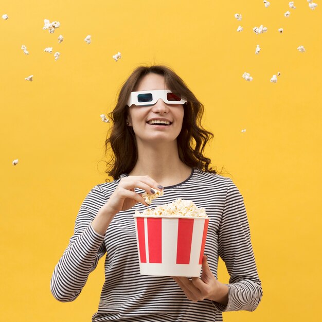 Front view woman with 3d glasses holding a bucket with popcorn