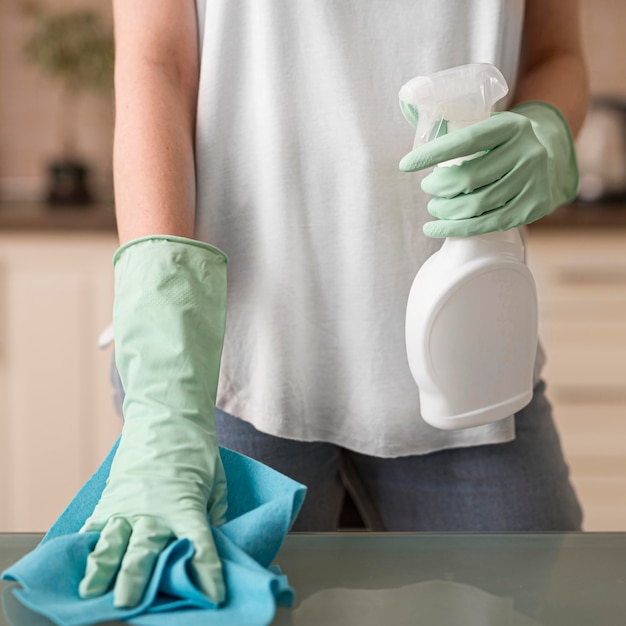 Free photo front view of woman with cleaning gloves holding cloth and cleaning solution