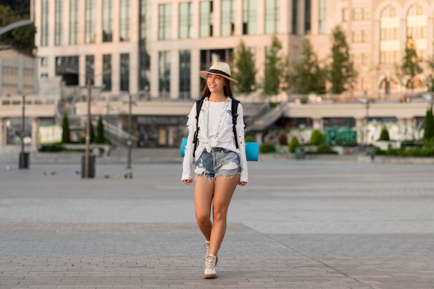 Front view of woman with hat carrying backpack while traveling alone