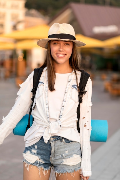 Front view of woman with hat carrying backpack while traveling