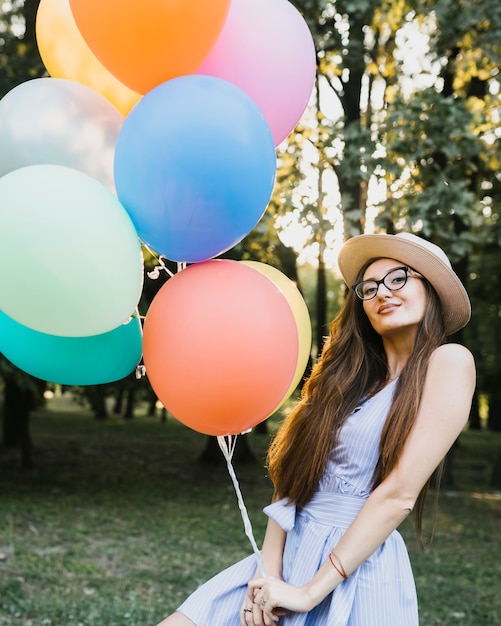 Free photo front view woman with hat holding balloons