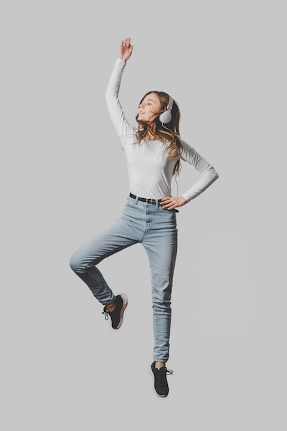 Free photo front view of woman with headphones jumping in the air