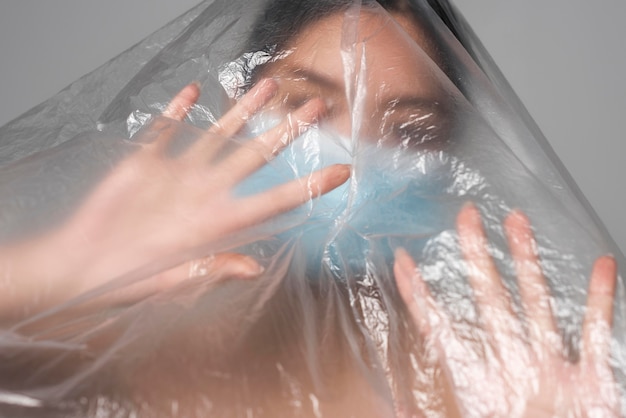 Free Photo front view woman with medical mask being covered in plastic