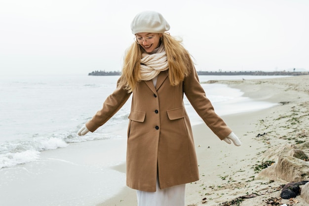 Free Photo front view of woman with mittens at the beach during winter