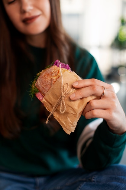 Free Photo front view woman with paper-wrapped sandwich