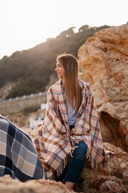 Free Photo front view woman with plaid blanket at the beach