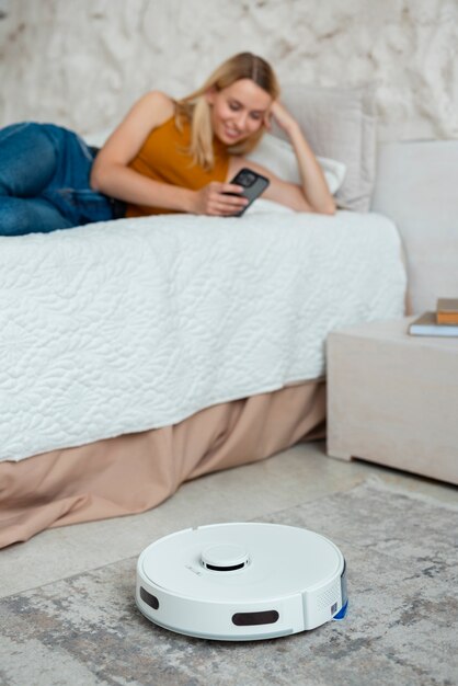 Front view woman with robotic vacuum cleaner at home