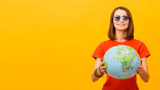 Free photo front view of woman with sunglasses holding globe with copy space