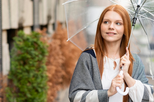 Front view woman with umbrella outdoors