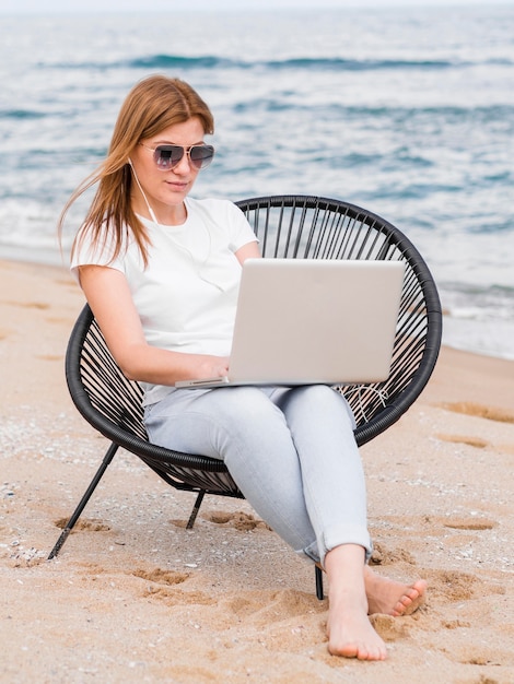 Free photo front view of woman working on laptop in beach chair