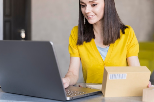 Free photo front view of woman working on laptop while holding box