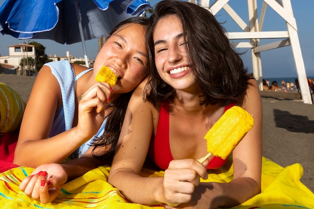 Free photo front view women eating ice cream on beach