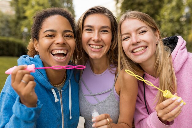 Front view women friends making soap bubbles