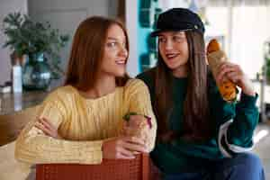 Free photo front view women holding  paper-wrapped sandwich