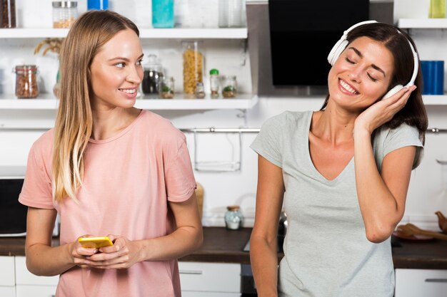 Front view of women at home listening to music on headphones