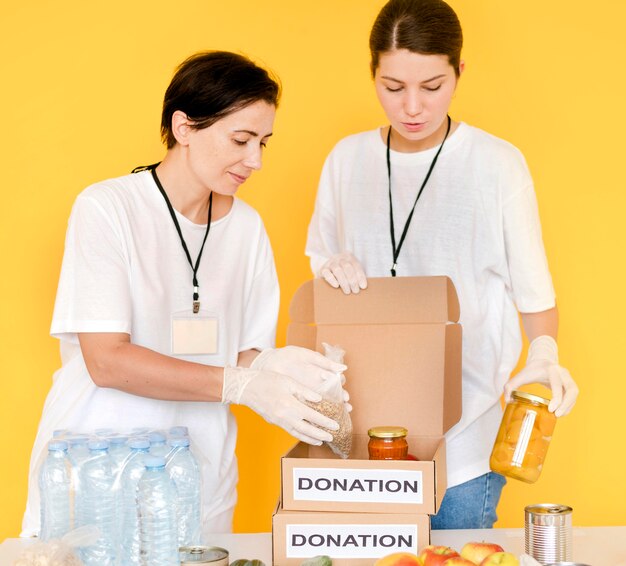 Front view of women putting food in donation box