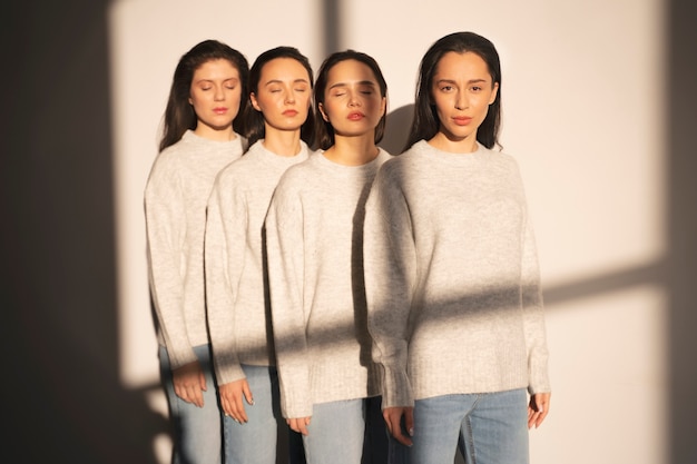 Front view of women in sweaters and jeans posing in window shadow