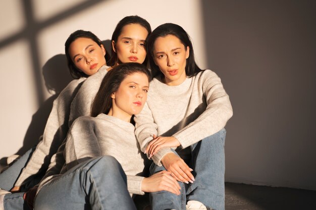 Front view of women in sweaters and jeans posing in window shadow