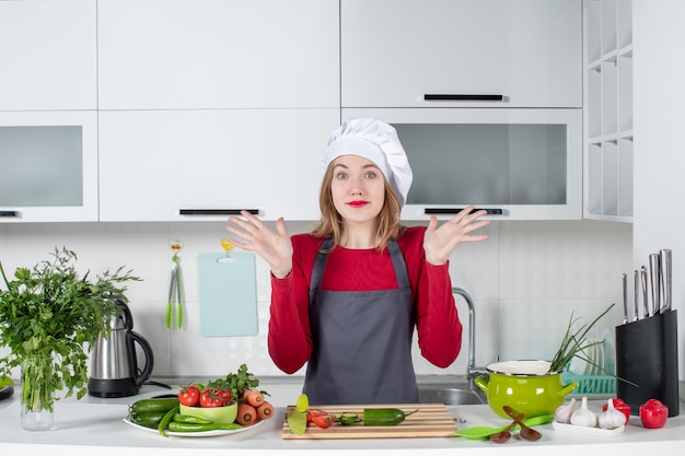 Front view wondered female cook in apron opening her hands