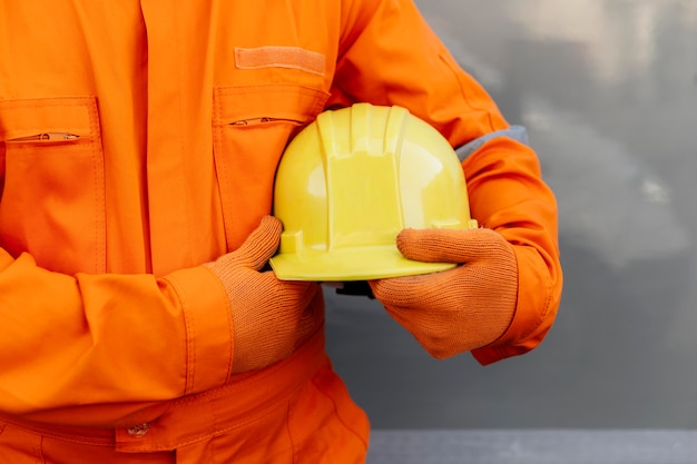 Free photo front view of worker in uniform holding hard hat