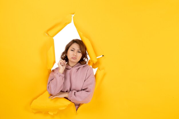 Front view of worried woman thinking deeply and free space on yellow torn