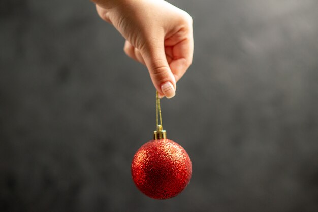 Front view xmas ball in female hand on dark free space