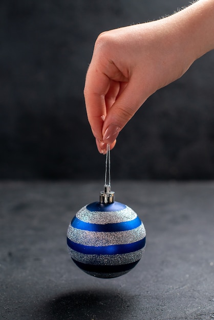 Free photo front view xmas tree ball in female hand on dark isolated background