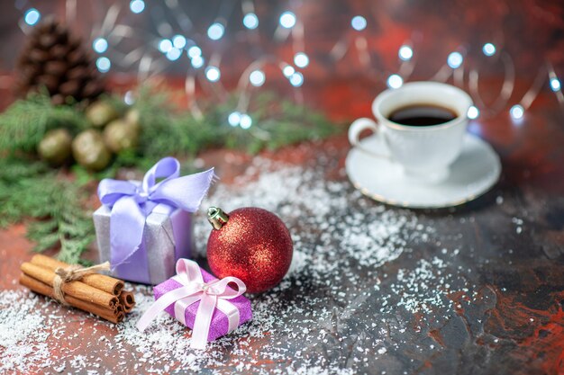 Front view xmas tree ball small gifts coconut powder cup of tea on dark