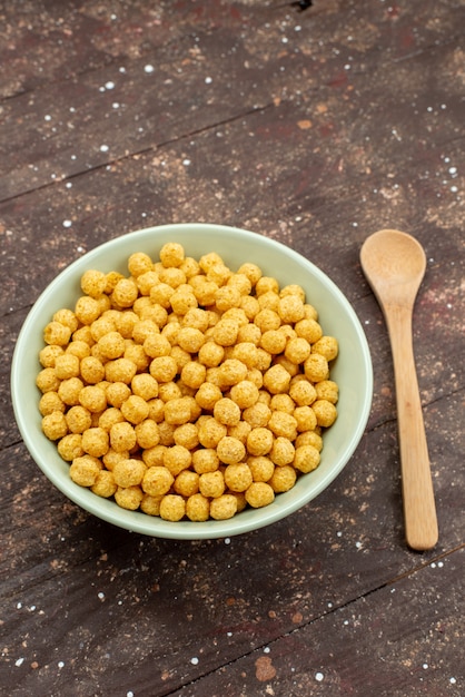 Free photo front view yellow cereals inside plate on dark wood, breakfast cornflakes cereals food