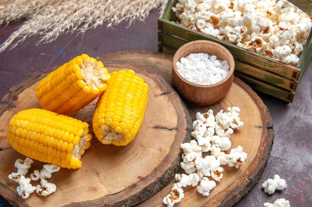 Front view yellow corns sliced with popcorn on a dark surface corn snack plants tree oil