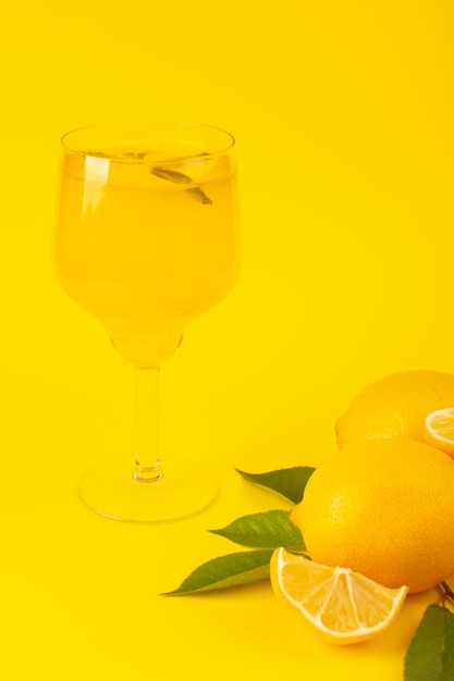 Free photo a front view yellow fresh lemons fresh ripe whole and sliced along with green leaves lemon drink fruits isolated on the yellow background citrus fruit color