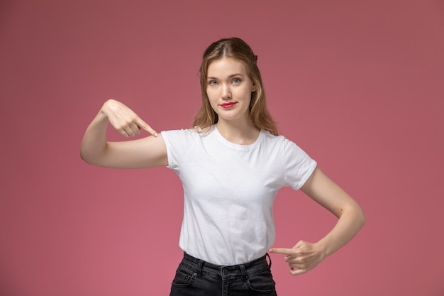 Front view young attractive female in white t-shirt posing with gesture on pink wall model color female young