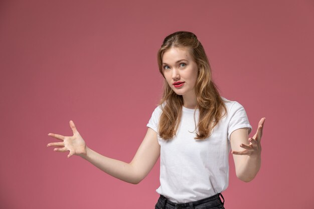 Front view young attractive female in white t-shirt posing with hand gestures on pink wall model female pose color photo