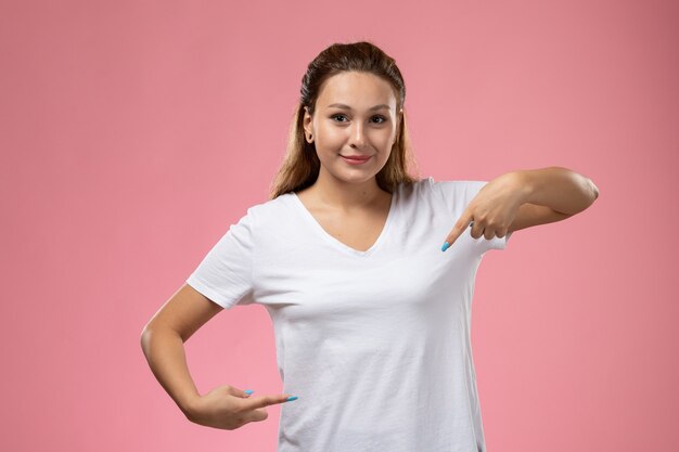 Front view young attractive female in white t-shirt posing with smile on pink background