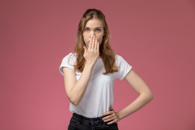 Front view young attractive female in white t-shirt posing with surprised expression on the dark-pink wall model color female young girl